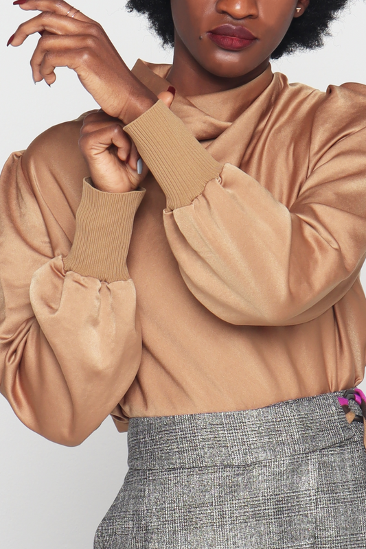 Black woman wearing High necked  with a hidden zipper at the back Slightly pleated shoulders: with long sleeves with elasticated cuffs Comfortable Made from super soft and shiny polyester fabric Monochromatic Camel color is definitely a standout.